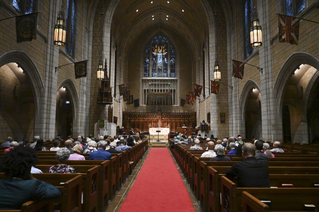 A joyous moment from the 2024 Convocation at the Church of St. Andrew and St. Paul, showing graduates in caps and gowns celebrating with faculty and family.